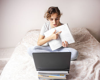 Man using mobile phone while sitting on bed at home