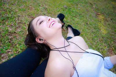 Happy beautiful woman lying down on feet of friend at park