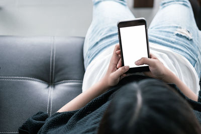 Midsection of man using mobile phone while sitting on sofa