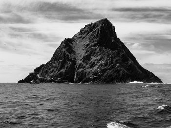 Rock formation by sea against sky