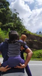Rear view of couple kissing against sky