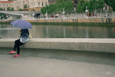 Woman with umbrella on lake in city