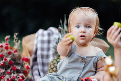 Portrait of cute girl holding fruit at park