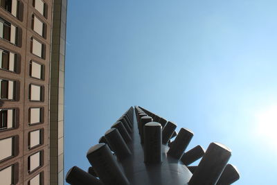 Low angle view of hand holding built structure against sky