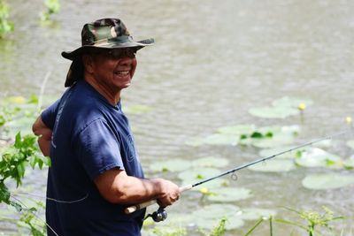 Mid adult man holding hat standing outdoors