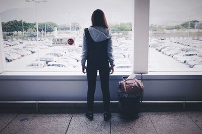 Rear view of woman standing by window