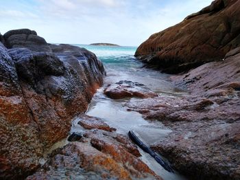 Rock formation on sea shore against sky