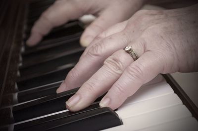 Close-up of cropped hand playing piano