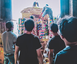 Rear view of people standing against wall in city