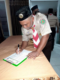 Low section of man holding paper while standing on table