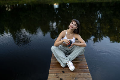 Portrait of young woman sitting on lake