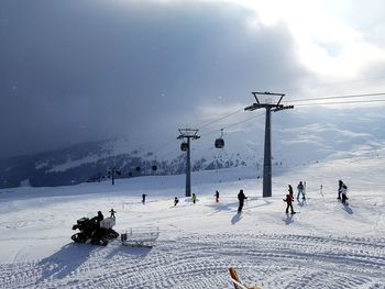 People skiing on field against snowcapped mountains