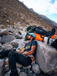 Full length of man sitting on rock against sky