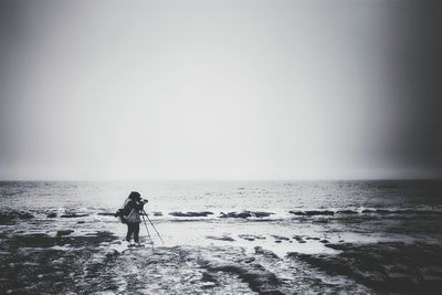 Man walking on beach against clear sky