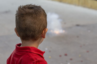 Rear view of boy by firework on road