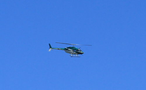Low angle view of helicopter flying against clear blue sky