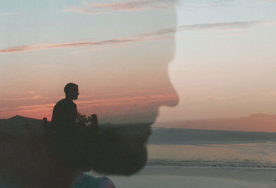 Silhouette man standing on beach against sky during sunset