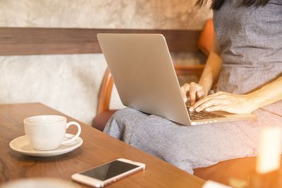 Midsection of man using laptop on table