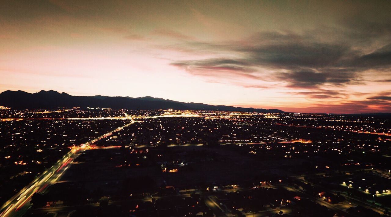 illuminated, city, cityscape, sky, night, high angle view, building exterior, built structure, architecture, cloud - sky, dusk, residential district, crowded, landscape, outdoors, city life, road, aerial view, no people, cloud