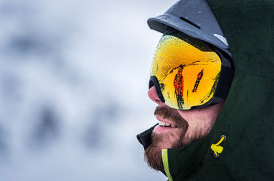 A bearded man with goggles and a helmet in the rain