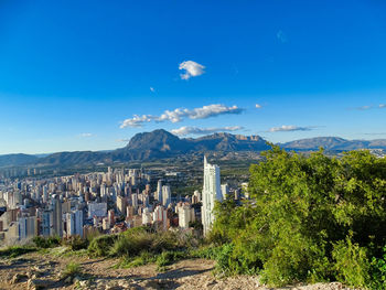 Aerial view of townscape against blue sky