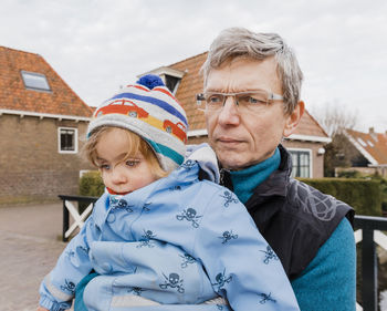 Grandfather carrying granddaughter in city