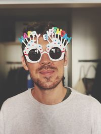 Portrait of man wearing birthday sunglasses prop at home