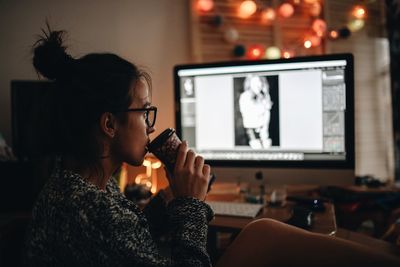 Side view of woman using mobile phone while sitting on table