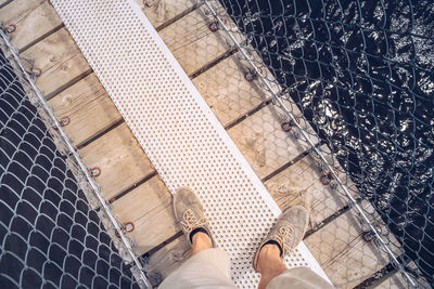 Low section of man standing on bridge over lake