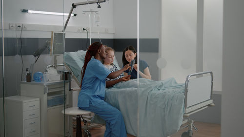 Mother and nurse sitting by girl at hospital