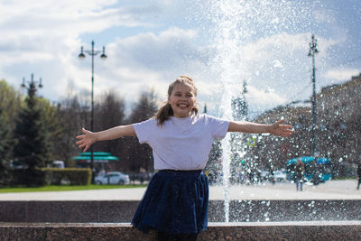 Happy little cute girl having fun in splashes a fountain