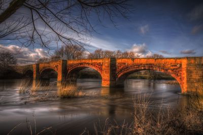 Arch bridge over river against sky