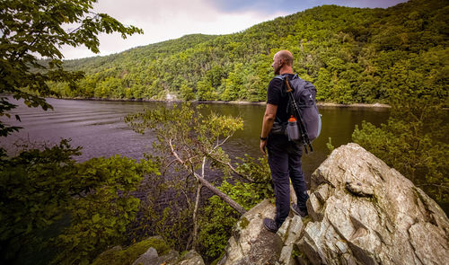 Rear view of man standing on rock by lake