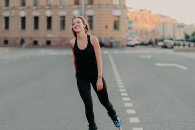 Young woman with umbrella on road in city