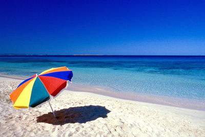 Multi colored umbrella on beach against clear blue sky