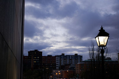 Low angle view of illuminated street light and buildings against sky