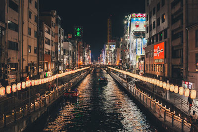 Canal amidst illuminated buildings in city at night