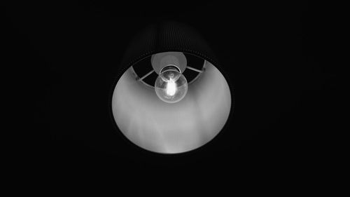 Close-up of illuminated light bulb against black background