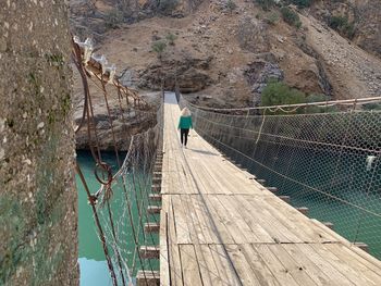 Rear view of woman walking on wooden foot bridge