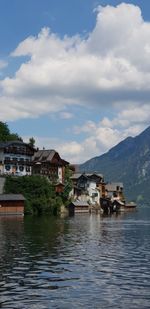 Houses by lake and buildings against sky