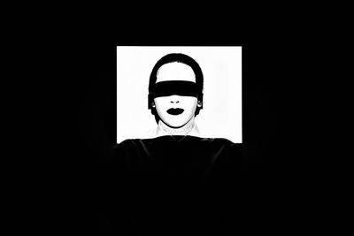 Woman with covered eyes against black background