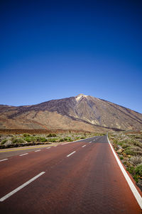 Empty road against clear blue sky