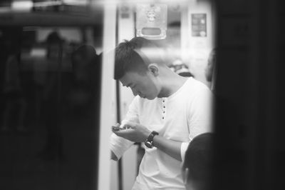 Side view of man looking through window