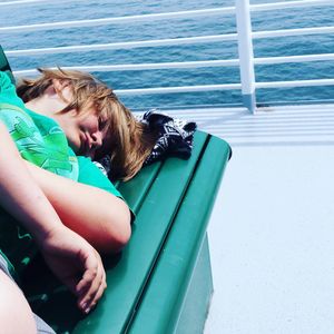 Boy sleeping on bench in boat