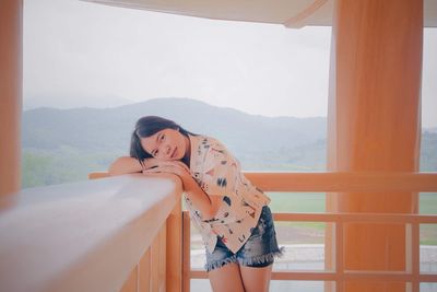 Portrait of teenage girl leaning on railing in balcony