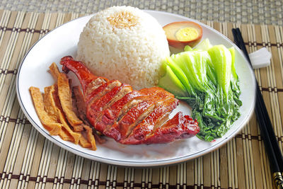 High angle view of roasted duck with rice in plate on place mat