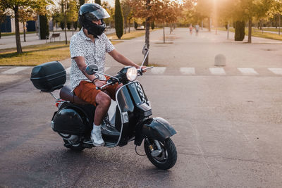 Young handsome male with hipster outfit rides a black vintage motorbike. he is a caucasian   male 