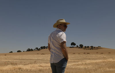 Rear view of man standing on field against clear sky