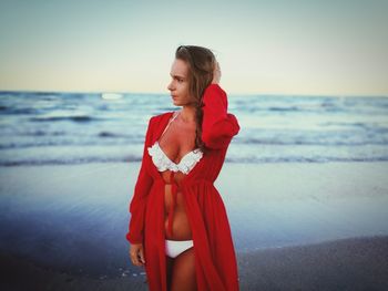 Sensuous woman in bikini standing on shore at beach