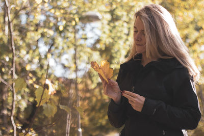 Midsection of woman holding plants against trees